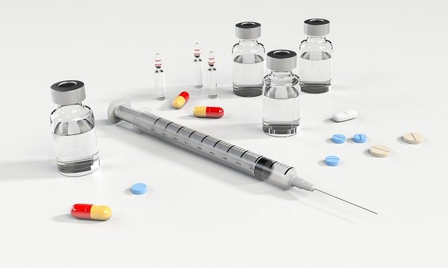 seringa, frascos para injeção e remédios na mesa